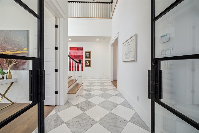 hall featuring baseboards, a high ceiling, and stairway