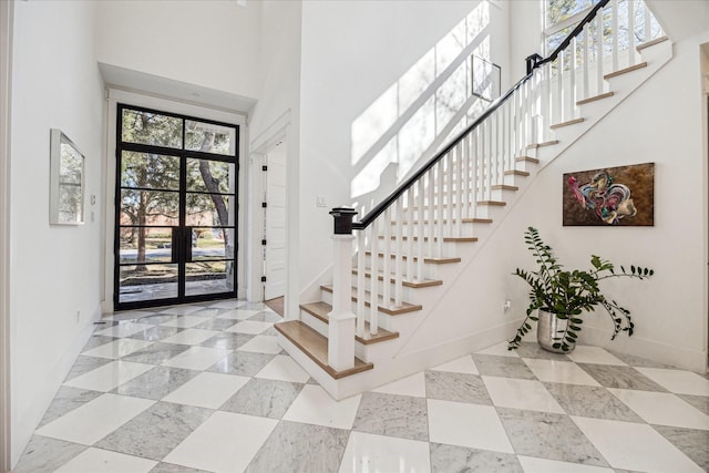 foyer entrance with stairs, a high ceiling, and baseboards