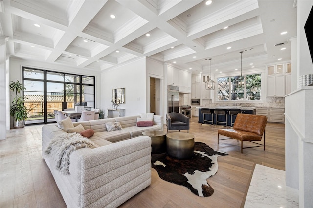 living area with light wood-type flooring, a high ceiling, coffered ceiling, and beam ceiling