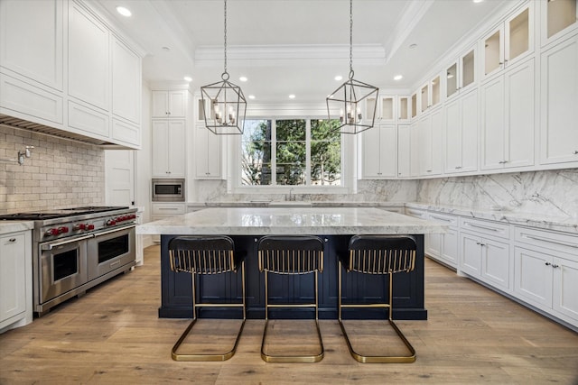 kitchen featuring appliances with stainless steel finishes, a tray ceiling, white cabinets, and a breakfast bar area