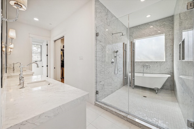 full bath featuring tile patterned flooring, a sink, a soaking tub, a shower stall, and a walk in closet