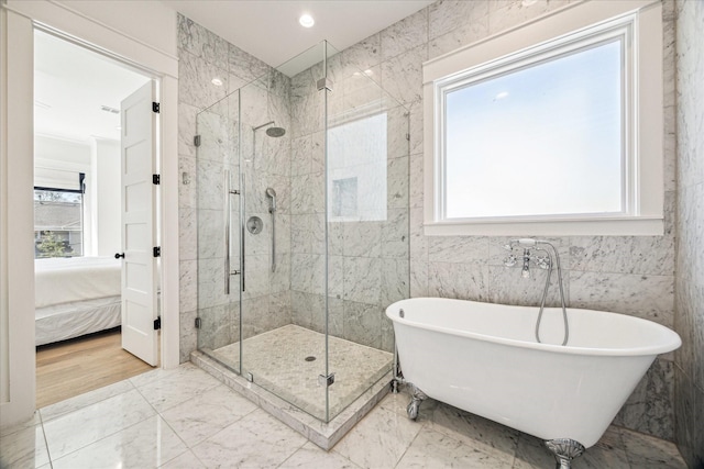 full bathroom with a stall shower, ensuite bath, marble finish floor, a freestanding tub, and tile walls