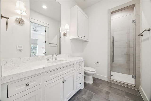 bathroom with a stall shower, baseboards, vanity, and toilet