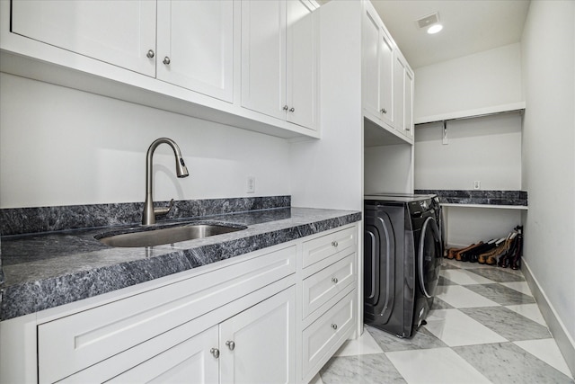 laundry area with a sink, visible vents, baseboards, cabinet space, and washer / clothes dryer