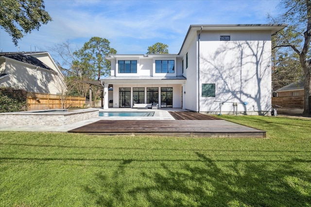 rear view of property featuring a fenced in pool, a lawn, fence, a deck, and stucco siding