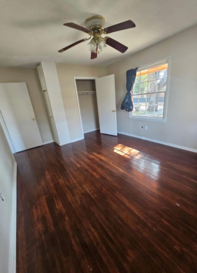 unfurnished bedroom featuring ceiling fan, a closet, wood finished floors, and baseboards