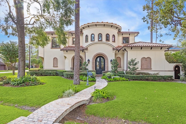 mediterranean / spanish home with stucco siding, french doors, a tile roof, and a front yard