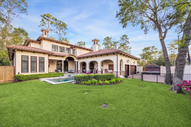 back of house featuring a tiled roof, a yard, and a fenced backyard