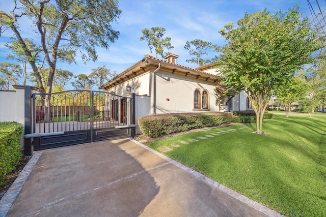 view of front of house with stucco siding, a tile roof, a front lawn, and a gate