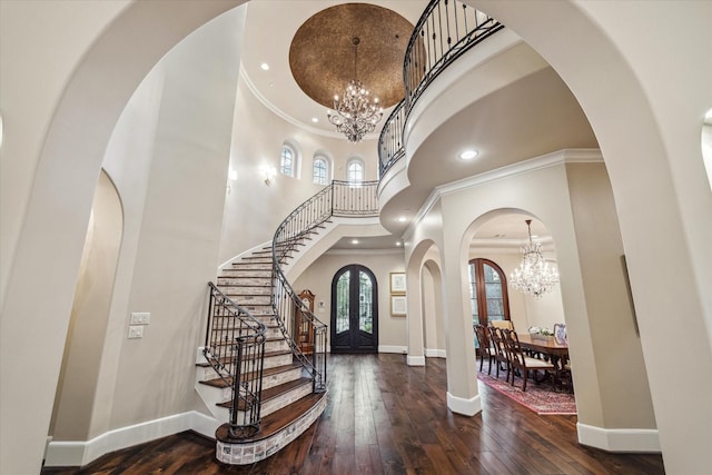 foyer entrance with a towering ceiling, wood-type flooring, baseboards, a chandelier, and stairs