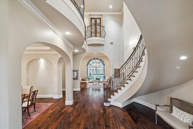 entrance foyer featuring ornamental molding, a high ceiling, baseboards, and hardwood / wood-style flooring