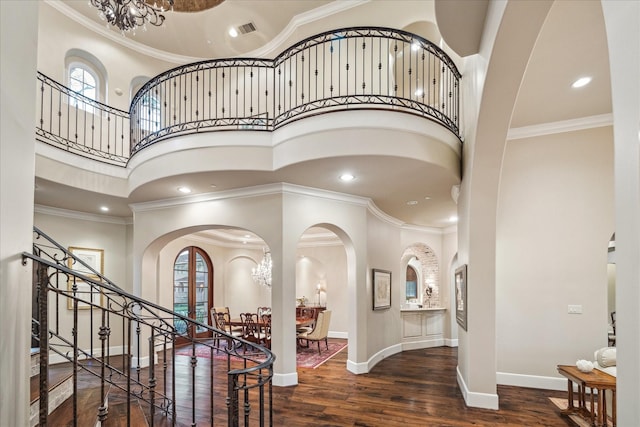 foyer entrance with crown molding, wood finished floors, and visible vents