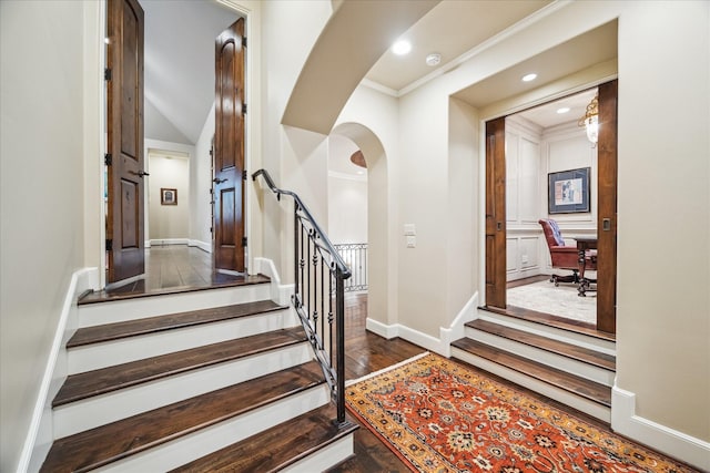 staircase featuring crown molding, baseboards, recessed lighting, wood finished floors, and arched walkways