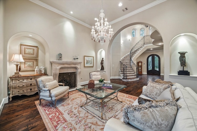 living room with a high end fireplace, stairs, an inviting chandelier, wood finished floors, and arched walkways