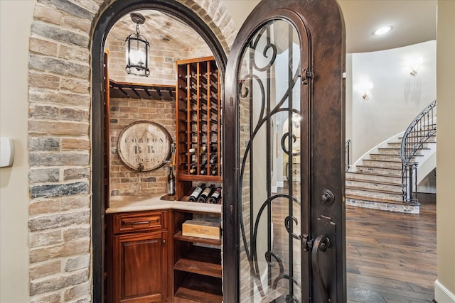 wine cellar featuring recessed lighting, brick wall, and wood finished floors