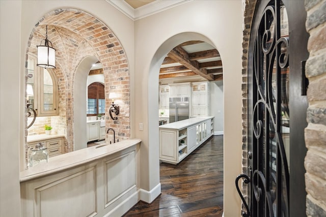 bar with baseboards, arched walkways, dark wood-style flooring, a sink, and stainless steel built in fridge