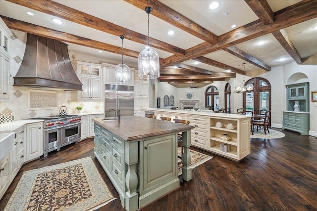 kitchen with green cabinetry, custom exhaust hood, an island with sink, a sink, and premium appliances