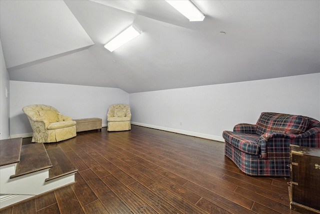 living area with vaulted ceiling, baseboards, and wood finished floors