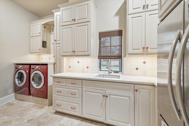 washroom featuring a sink, cabinet space, baseboards, and separate washer and dryer