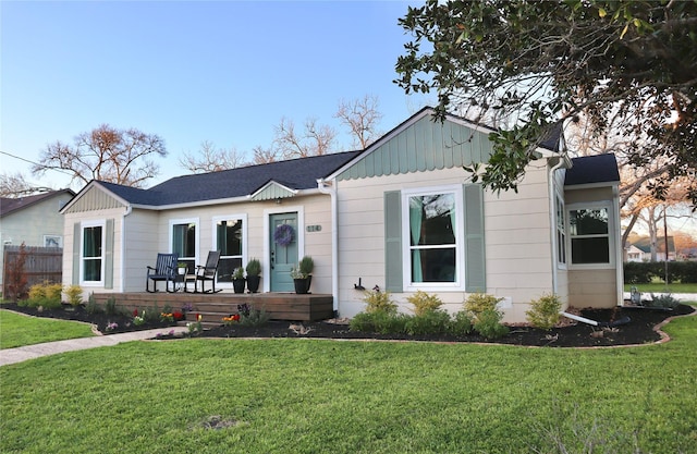 single story home featuring a porch, board and batten siding, a front lawn, and fence