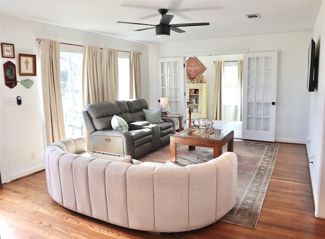 living room featuring visible vents, baseboards, wood finished floors, and a ceiling fan