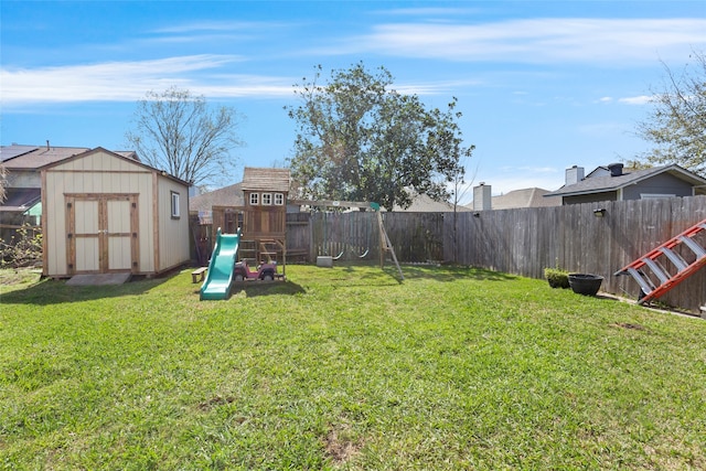 view of yard with a fenced backyard, a shed, a playground, and an outbuilding