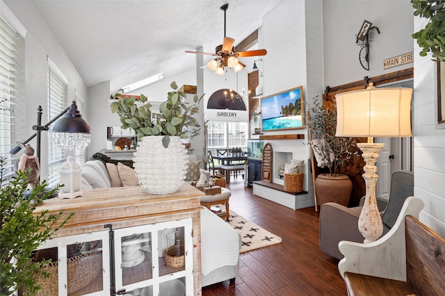 living room featuring a textured ceiling, high vaulted ceiling, ceiling fan, a multi sided fireplace, and hardwood / wood-style floors