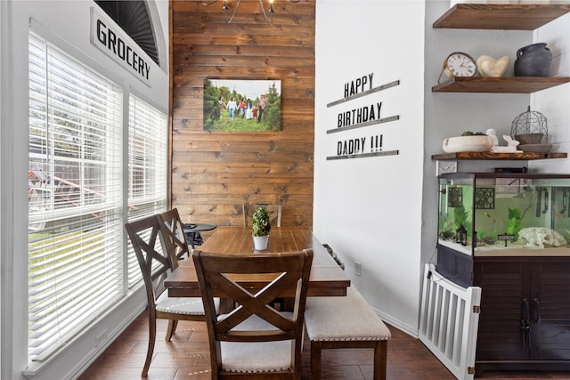 dining space featuring dark wood-style floors and wood walls