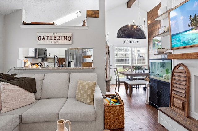 living area featuring dark wood-style floors, beam ceiling, high vaulted ceiling, and a notable chandelier