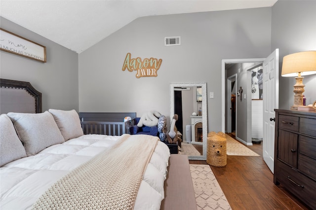 bedroom featuring high vaulted ceiling, a fireplace, dark wood finished floors, and visible vents