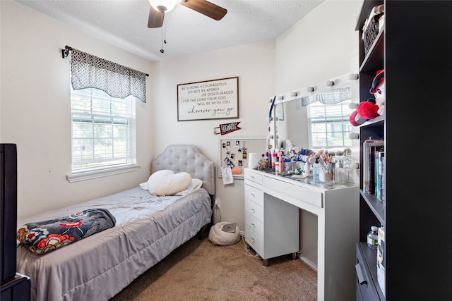 bedroom featuring light carpet, a textured ceiling, and a ceiling fan