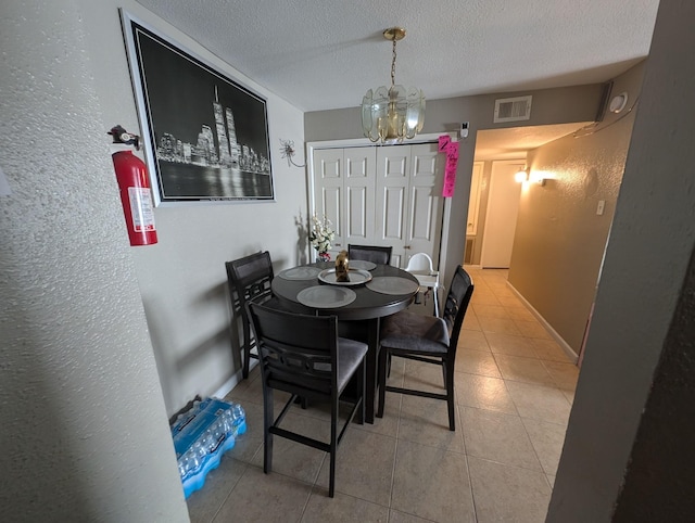 dining space featuring a textured ceiling, tile patterned flooring, visible vents, and an inviting chandelier