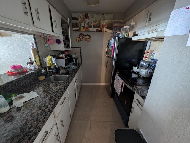 kitchen with white microwave, black range with electric cooktop, light tile patterned flooring, under cabinet range hood, and white cabinets