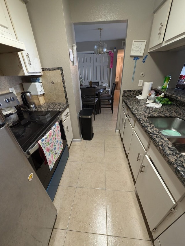 kitchen featuring electric range, a chandelier, decorative backsplash, white cabinetry, and light tile patterned flooring