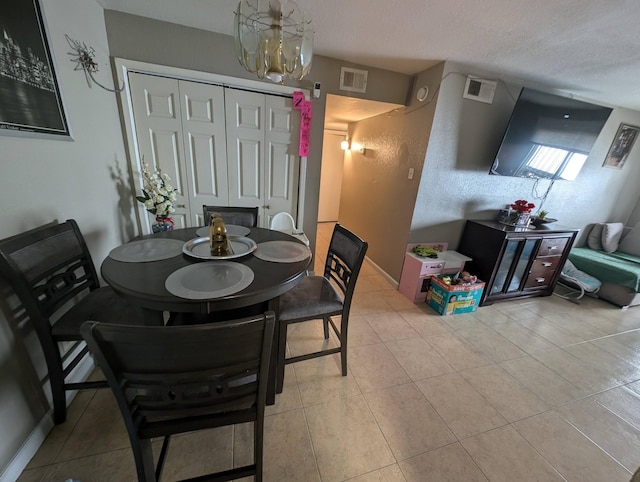 dining room featuring baseboards, visible vents, a textured ceiling, and light tile patterned flooring