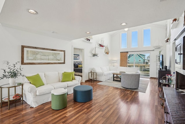 living room featuring recessed lighting, a towering ceiling, and wood finished floors