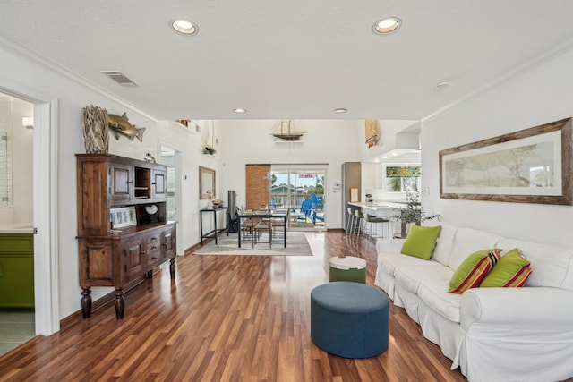 living area with recessed lighting, wood finished floors, visible vents, baseboards, and crown molding