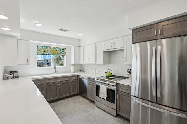 kitchen featuring a sink, stainless steel appliances, light countertops, white cabinetry, and backsplash