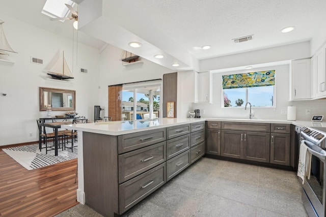 kitchen with visible vents, a peninsula, a skylight, and stainless steel range with electric stovetop