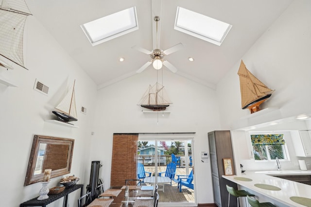 interior space featuring high vaulted ceiling, a skylight, and visible vents