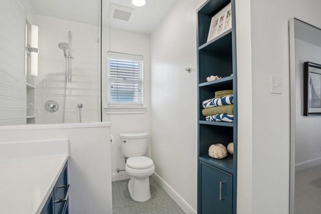 bathroom featuring visible vents, toilet, a tile shower, vanity, and baseboards