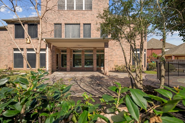 back of house featuring brick siding, a patio, and fence