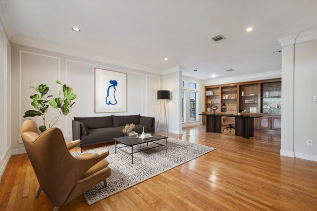 living area with light wood finished floors, a decorative wall, and crown molding