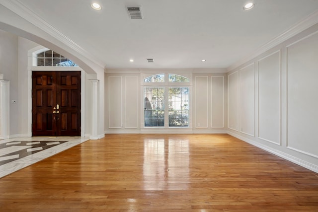 foyer entrance with visible vents, light wood finished floors, and a decorative wall