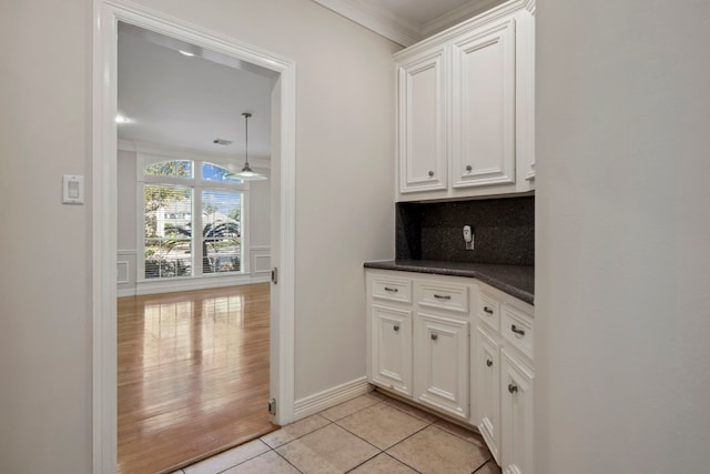 4207 Clearwater Ct, Missouri City, TX 77459 - kitchen with light tile patterned floors, ornamental molding, white cabinetry, dark countertops, and backsplash