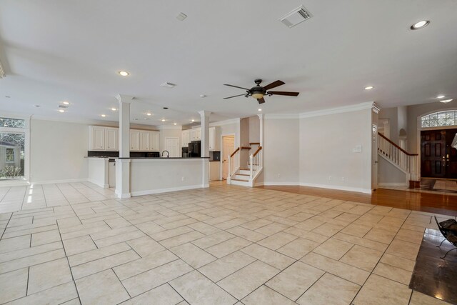 unfurnished living room featuring visible vents, stairs, decorative columns, light tile patterned floors, and ornamental molding