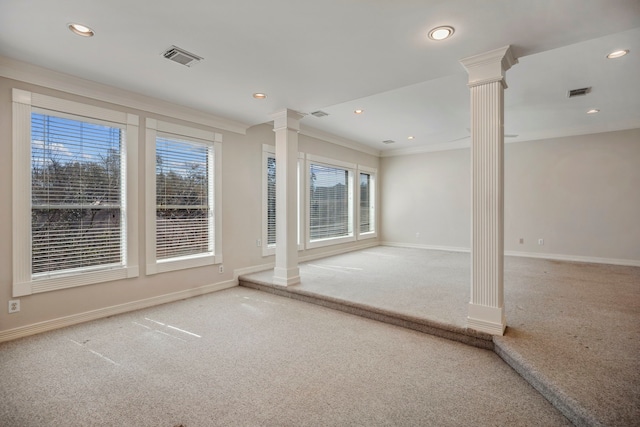 unfurnished room with crown molding, decorative columns, carpet, and visible vents