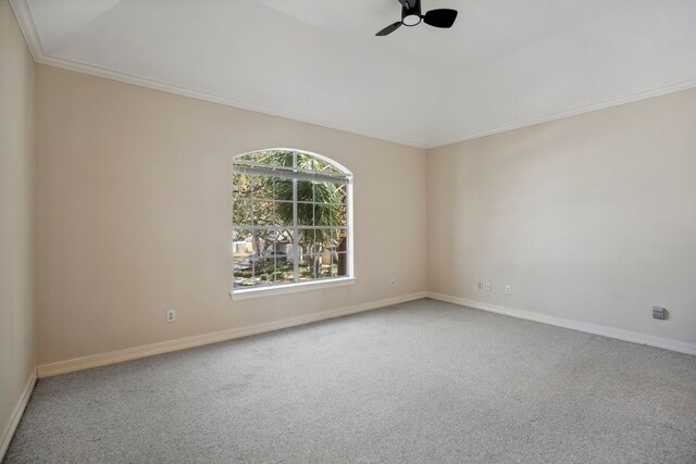 carpeted empty room with vaulted ceiling, crown molding, baseboards, and ceiling fan