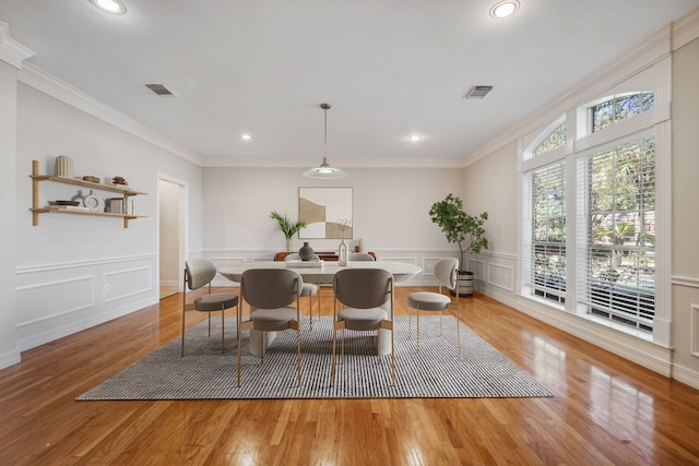 dining space featuring visible vents, ornamental molding, and light wood finished floors