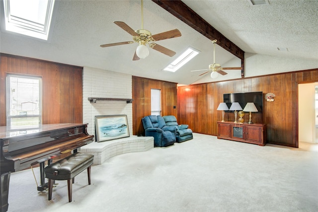 living room featuring carpet floors, a fireplace, lofted ceiling with skylight, wood walls, and a textured ceiling